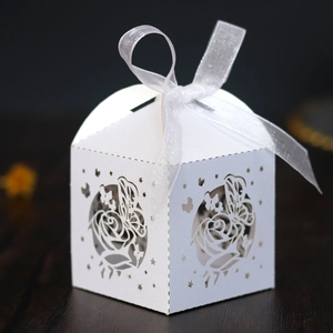 Detail of white laser-cut wedding favor box with butterfly and rose patterns