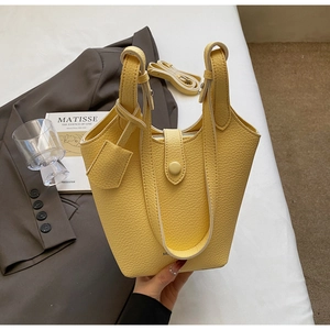 Detail of bright yellow bucket bag featuring textured leather and a thick top handle