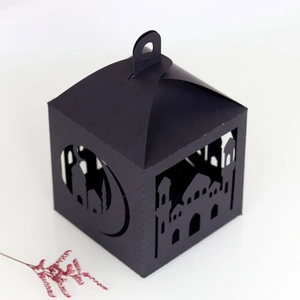 Close-up of black laser-cut paper gift box featuring mosque and crescent moon patterns