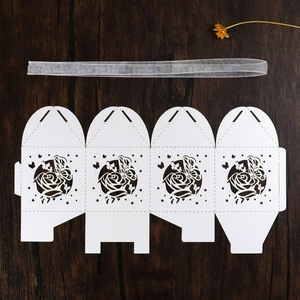 Flat lay of white laser-cut wedding candy boxes with rose and butterfly patterns