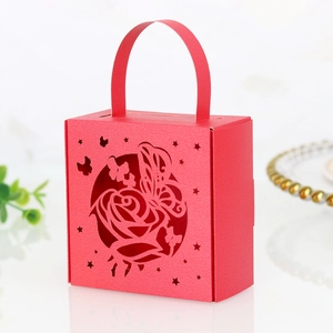 Detail of red laser-cut candy box with rose and butterfly patterns and handle