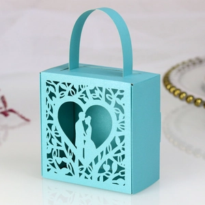 Detail view of laser-cut light blue wedding candy box with heart and couple silhouette