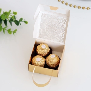 Detalle del diseño calado con láser en caja de regalo dorada con asa de cinta elegante