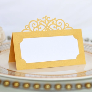 Macro detail of laser-cut golden table card with elegant floral vines and pearlescent texture