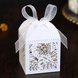 Macro detail of laser-cut tropical leaf patterns on a white wedding favor gift box