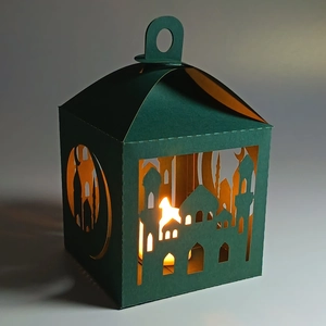 Detail of dark green paper lantern with laser-cut moon and mosque patterns