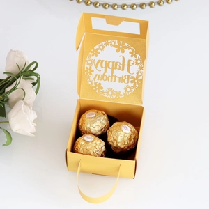 Detail of laser-cut Happy Birthday hollow text inside a golden gift box with chocolates
