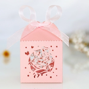 Detail of pink laser-cut wedding favor box with rose and butterfly patterns