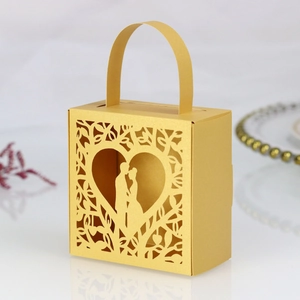 Macro view of laser-cut heart pattern and couple silhouette on golden wedding gift box