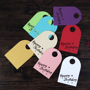 Primer plano de 8 etiquetas de regalo coloridas de Happy Birthday sobre madera oscura