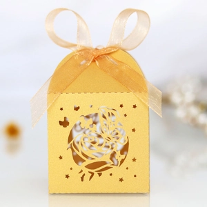 Detail of laser-cut glitter gold wedding candy box with rose butterfly and orange ribbon