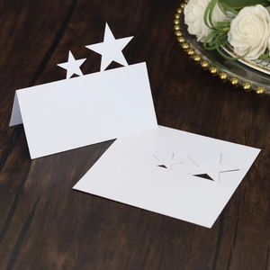 Macro detail of white hollow star place cards on a dark wood grain background