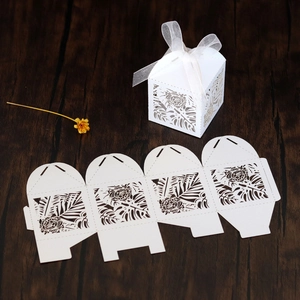 Detail of white laser-cut gift box with tropical leaf patterns and white silk ribbon
