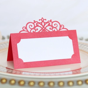 Detail of red laser-cut place card with elegant vine patterns on a white dinner plate