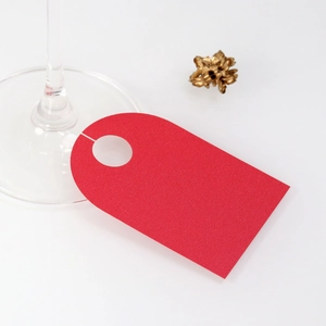 Macro detail of red wine glass place card showing U-shaped hanging hole on white background