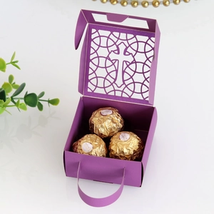 Détail boîte cadeau violette découpée au laser avec motif croix et chocolat doré