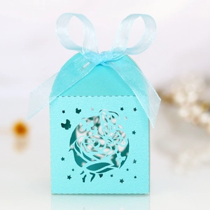 Detailed laser-cut blue wedding favor box with rose patterns and organza ribbon