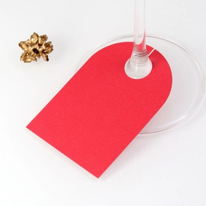 Close-up of red textured paper place card attached to a wine glass stem for wedding decor