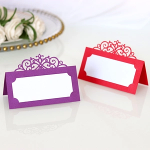 Macro detail of laser-cut wedding place cards in purple and red on a luxury table