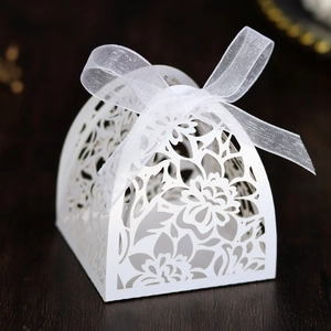 Detail of white laser-cut floral wedding candy box with elegant organza ribbon bow