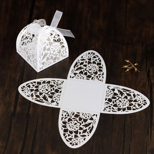 Detailed laser-cut white wedding candy box featuring floral hollow patterns and ribbon