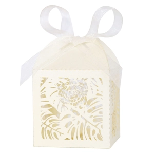 Macro shot of ivory laser-cut gift box with tropical leaf patterns and white organza ribbon