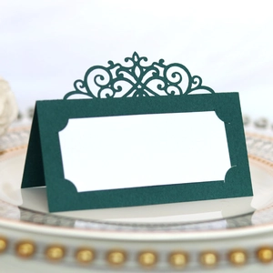 Close-up of laser-cut green place card with intricate European vine patterns on a plate