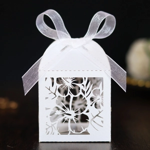 Macro detail of laser-cut tropical leaf patterns on a white wedding favor candy box
