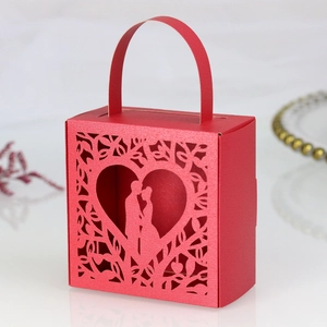 Detail of red laser-cut wedding favor box with heart-shaped couple silhouette and handle