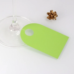 Close-up of a light green blank card tag attached to a wine glass stem for wedding decor