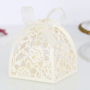 Detail of laser-cut hollow floral pattern and white ribbon bow on an elegant wedding favor box