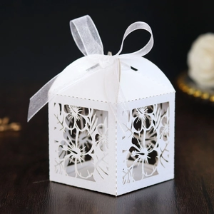 Laser-cut white wedding favor box with floral patterns and white organza ribbon bow
