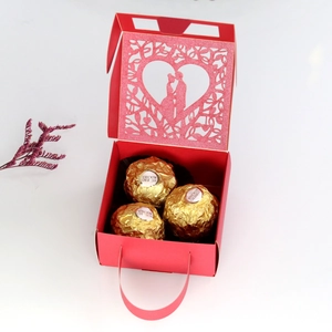 Detail of red laser-cut heart favor box showing intricate wedding couple silhouette