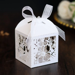 Detail of white laser-cut wedding favor box with floral patterns and a ribbon bow