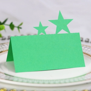 Detail view of a green hollow star seat card on an elegant ceramic tray for events