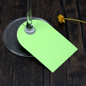 Close-up of neon green paper wine glass markers on a rustic dark wood background