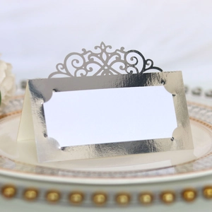 Macro shot of silver laser-cut place card with scroll pattern on a fine porcelain plate