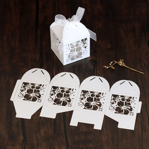 Detailed laser-cut floral pattern on a white candy box with ribbon and wooden background