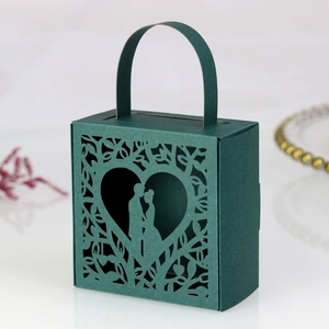 Detail of dark green laser-cut wedding gift box with heart and couple silhouette