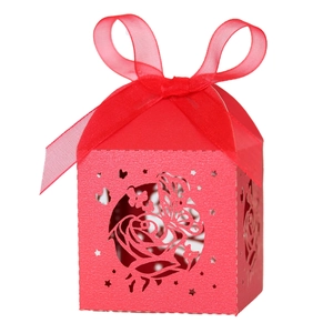 Detail view of red laser-cut candy box with rose patterns and a silk ribbon bow