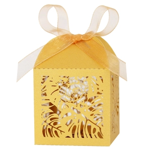 Close-up of golden laser-cut gift box with tropical leaf patterns and ribbon bow