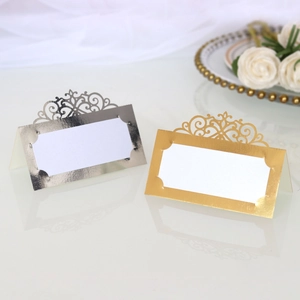 Detail of laser-cut hollow pattern on gold and silver wedding place cards with white rose