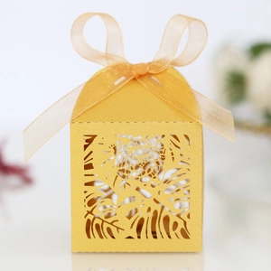 Macro view of yellow laser-cut gift box featuring monstera leaf patterns and a ribbon bow
