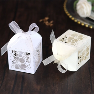 Detailed laser-cut floral candy gift boxes in white and beige with organza ribbons