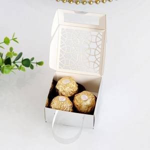 Détail de boîte à dragées blanche découpée au laser avec motif croix et chocolat
