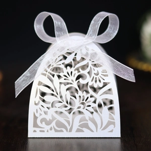 Close-up of white laser-cut wedding favor box with floral patterns and organza ribbon