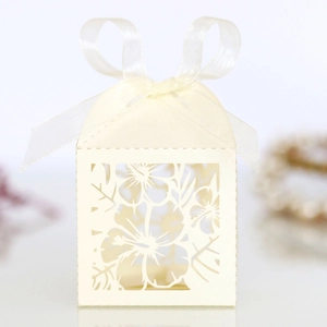 Detail of laser-cut floral pattern on cream candy box with elegant ribbon bow