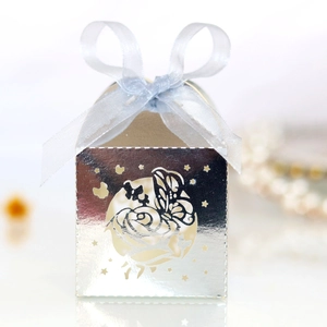 Close-up of silver laser-cut wedding candy box with a butterfly pattern and blue ribbon