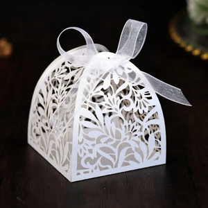 Detailed laser-cut floral pattern on white wedding favor box with a white organza ribbon bow