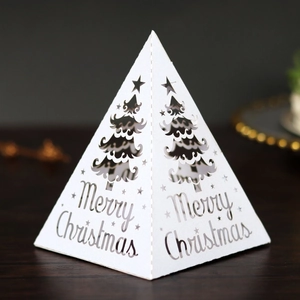 Detailed laser cut Christmas tree pattern on white pyramid gift box with Merry Christmas text